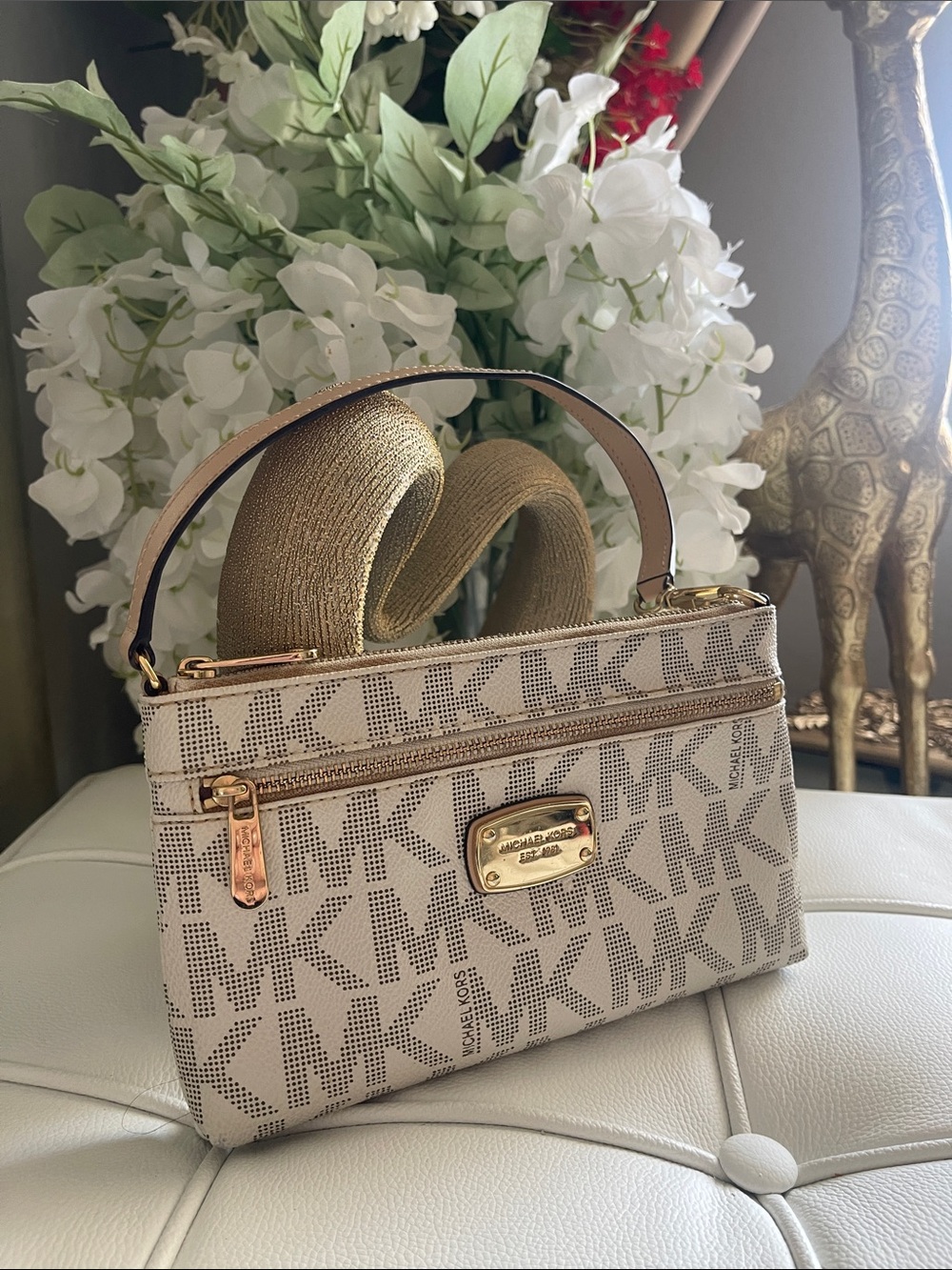 This is a Michael Kors Jet Set wristlet in a cream and gold logo design